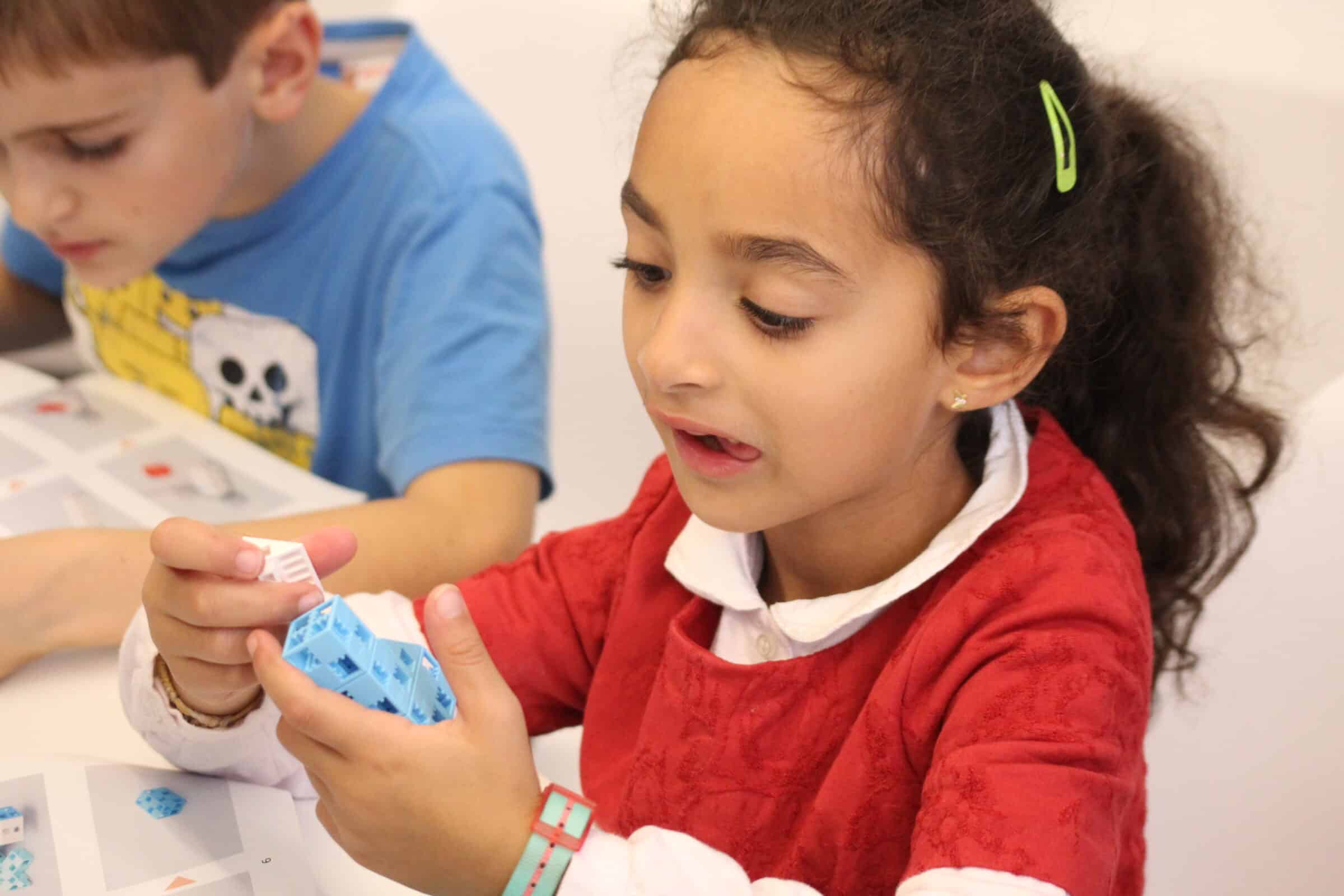 petite fille concentrée à assembler les pièces de son robot
