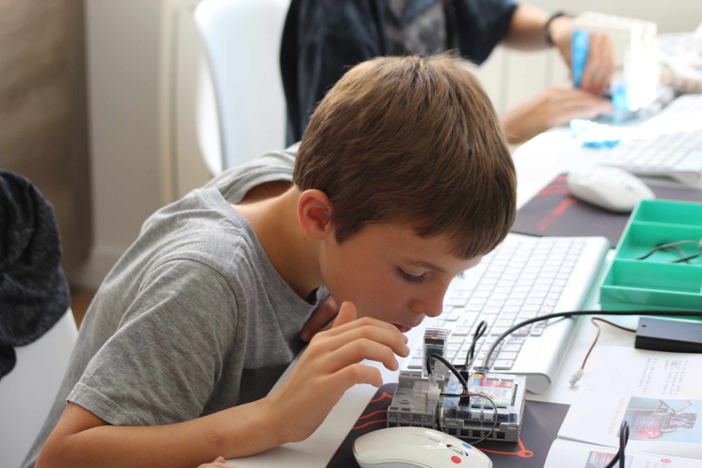 garçon 9-14 ans regardant très près son robot connecté lors d'un atelier au club de Niort