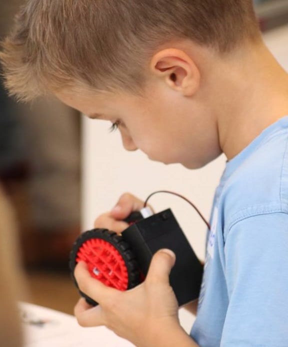 Cours 6-9 garçon touchant les roues de son robot