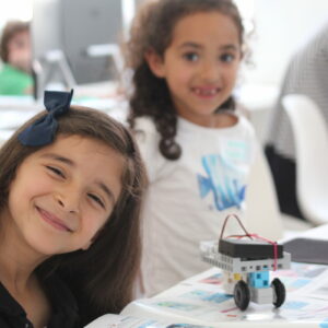 deux filles souriantes avec des robots lors d'un atelier arduino