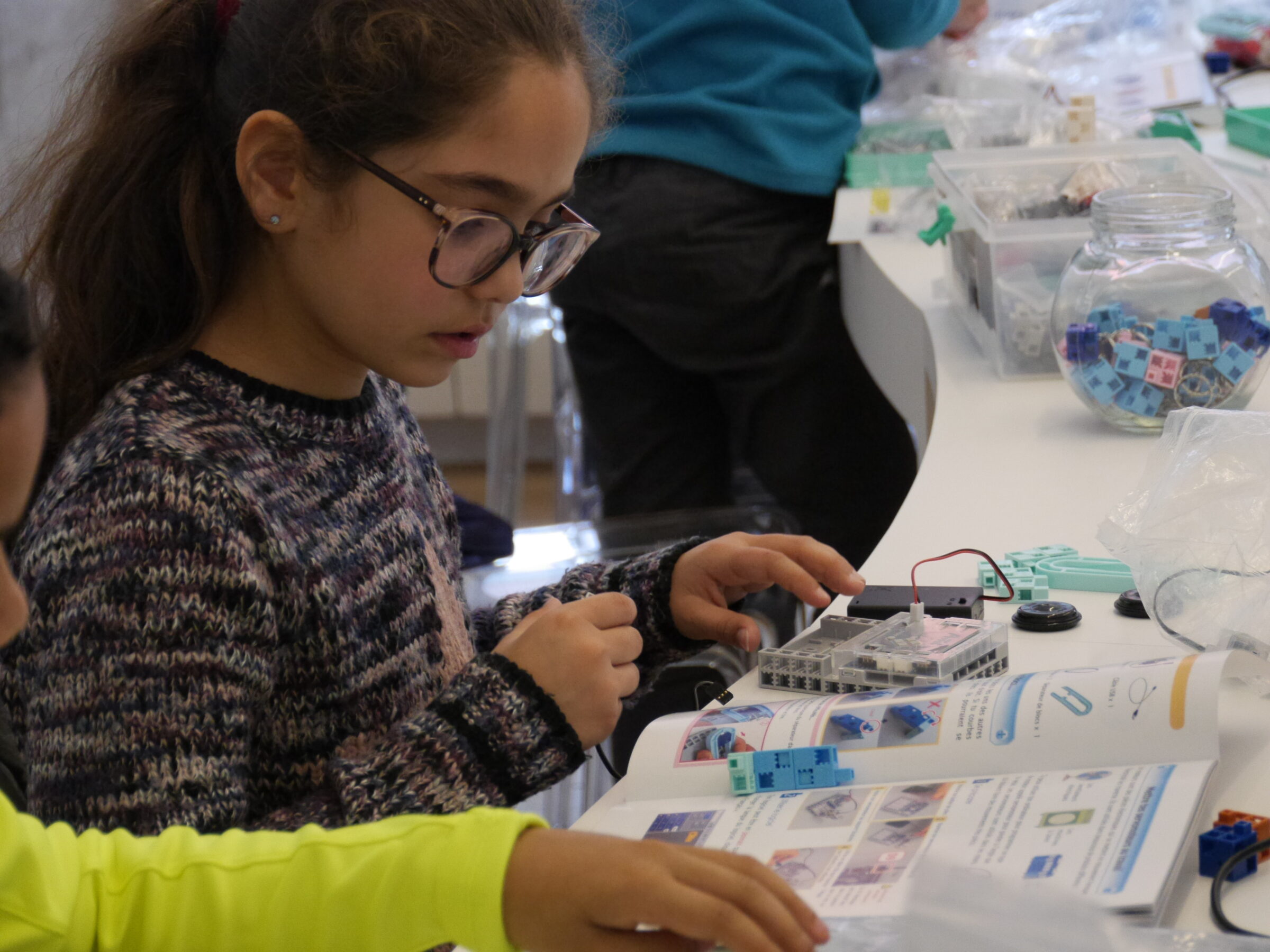 fille à lunettes réalisant le montage de son robot