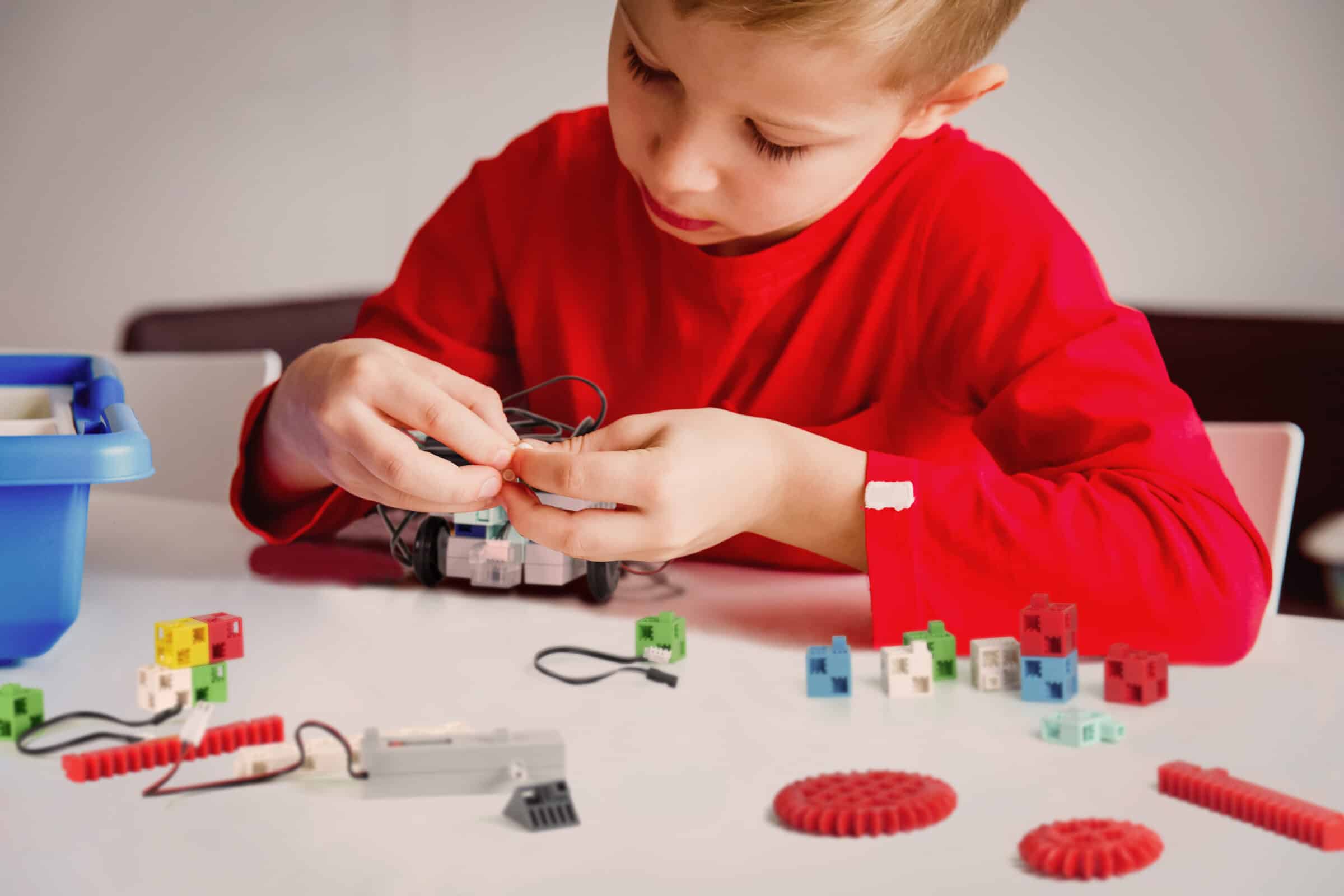 little boy building robot at robotic technology school lesson