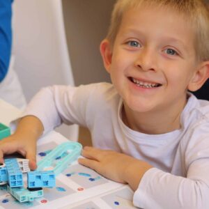 garçon souriant avec son crocobot dans la main lors d'un cours